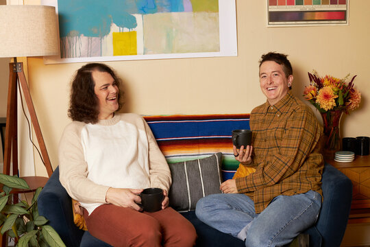 lifestyle portrait of transgender nonbinary friends talking on couch
