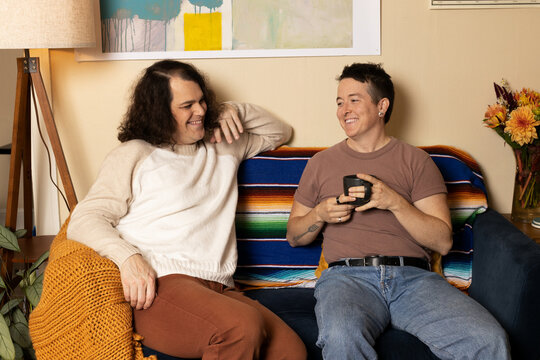 lifestyle portrait of transgender nonbinary friends talking on couch