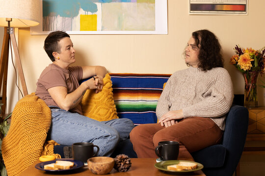 lifestyle portrait of transgender nonbinary friends talking on couch
