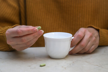 The middle-aged woman dressed in a warm sweater taking a pill