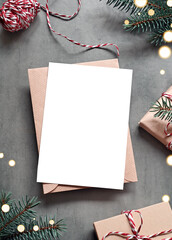 Blank white paper card with brown envelop, Christmas pine and handmade gift box on grey background.