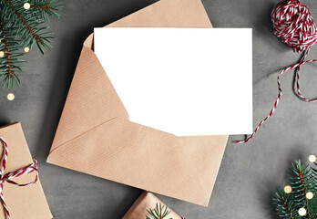 Blank white paper card with brown envelop, Christmas pine and handmade gift box on grey background.