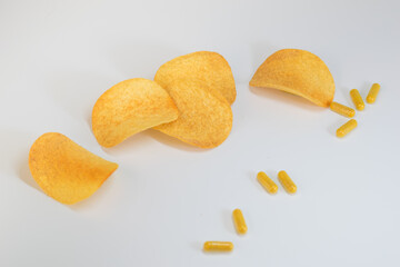 Scattered chips and capsules with dietary supplements, cholesterol treatment concept, unhealthy food
