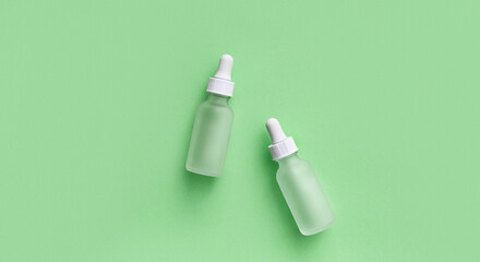 Two white matte bottles on pastel green background. SPA natural organic cosmetics. Glass cosmetic bottles with pipette, anti aging serum, collagen, peptides, cosmetics mockup, skincare concept. Flat