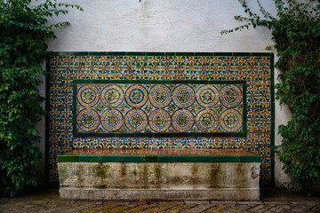 Old vintage andalusian bench with green ceramic tile pattern and plants close-up