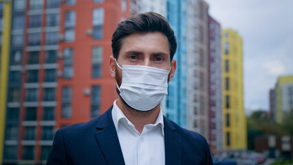Close up portrait of businessman wearing medical mask put on face respirator follow quarantine measures man working on city street use personal protection from coronavirus outbreak health care concept