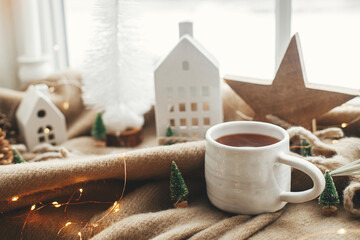 Christmas still life, winter hygge home. Warm cup of tea, christmas decorations, lights, little...