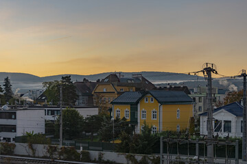 Fototapeta na wymiar sunrise over a European provincial town against a dark sky, morning fog over the houses.
