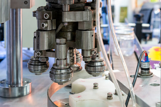 Close up capping head or sealing roller component of can cap seamer machine for manufacturing process in food or beverage filling and packing industrial