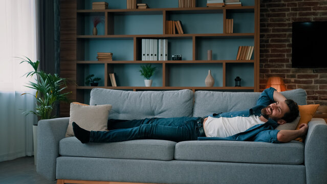 Exhausted Caucasian Man Jumping On Soft Couch In Living Room Falling Down On Comfortable Sofa Enjoy Daily Nap Healthy Rest After Working Day Has Pleasure Relaxation Time Carefree Weekend At Home Alone