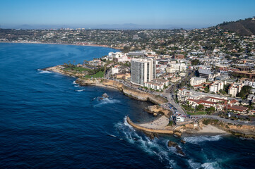 Aerial image of Children's Pool by Seal Rock in La Jolla San Diego California with mountains in the background and palm tree lined roads - obrazy, fototapety, plakaty