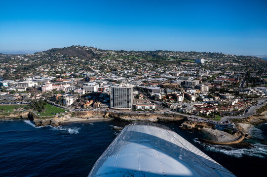Aerial image of Children's Pool in La Jolla San Diego California with Mount Soledad in the background and airplane wing in the foreground