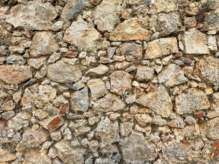Background, texture, stone wall of round stones cobblestones bricks natural surface natural sharp convex rough stone cobblestone with cracks
