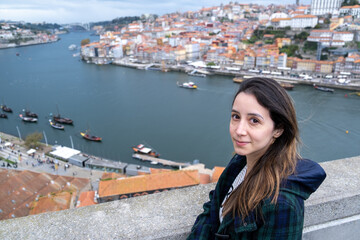 Fototapeta na wymiar Young woman traveller smiling and looking at the camera Douro river and the city of Porto, Portugal on background