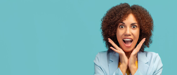 Happy young African American woman with curly hair screaming wow on blue background. Good news, sale, shopping or big discounts concept