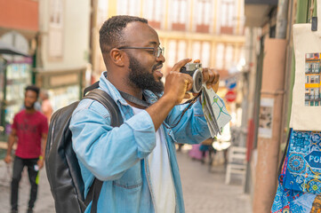 Smiling young african american man with cmera against european cozy street. Travel in Portugal