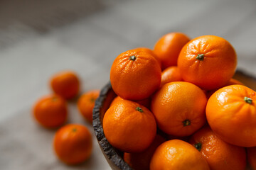 Basket with tangerine or orange fruit on a gray plaid background.