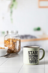 Mug of morning coffee on white tile tabletop in kitchen. Healthy breakfast consept with coffee and muesli. Text space