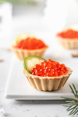 Festive Christmas appetizer tartlets stuffed with red caviar and a slice of lime on a white tray. Tasty snack for christmas or new year holiday food recipe