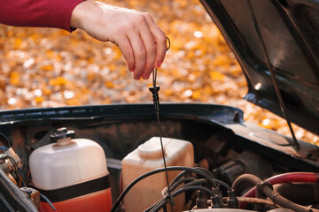 A man checks the oil level in the car engine. Self-service of the car. Periodic check of the oil...