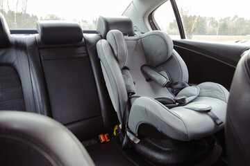 Child car seat for safety in the rear passenger seat of a car - obrazy, fototapety, plakaty