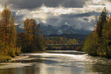 Moody fall day along the Snoqualmie River under threating clouds and with glistening water in the Pacific Northwest of the United States