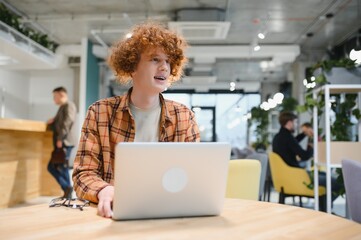 Caucasian hipster guy enjoying distance job in coffee shop, male freelancer in trendy glasses...