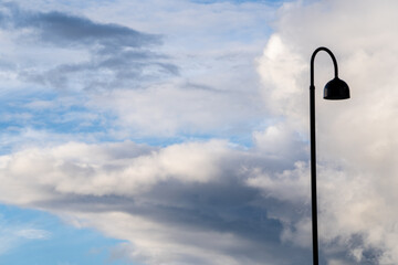 Bright blue cool autumn sky with some light light transparent clouds with long black lanterns in the foreground.