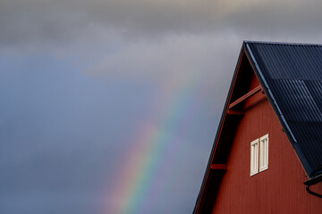 Bright blue cool autumn sky with some light light transparent clouds with a dark red house roof facade in the foreground