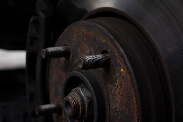 Close-up photo of brake disc with dirty bolts in the shop for maintenance. Maintenance of brake discs. Mechanical concept