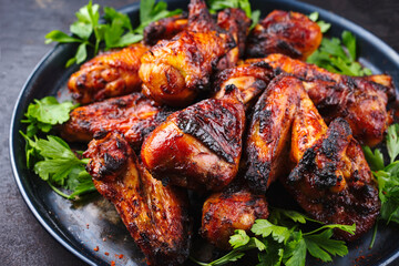 Traditional barbecue chicken wings and drumsticks with hot chili and coriander served as close-up on a rustic plate