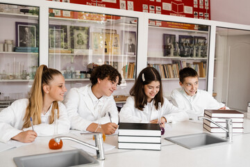 Chemistry lesson in labaratory in school. Pupils writing homework, smiling and having fun together in school laboratory.