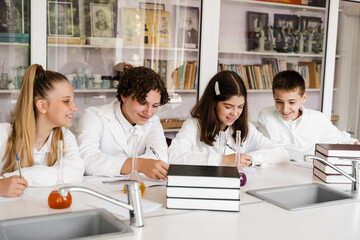 Chemistry lesson in labaratory in school. Pupils writing homework, smiling and having fun together...