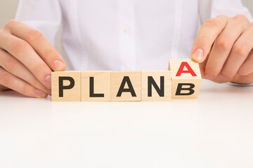 businessman hand flipping wooden cube blocks with PLAN A change to PLAN B text on table background. strategy, analysis, marketing, project and crisis concepts.