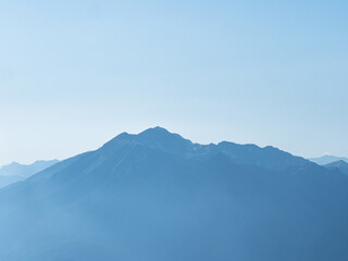 Light blue mountains in the distance, aerial perspective, mountain atmosphere. Beautiful mountain landscape, clouds over the peaks of the mountains,