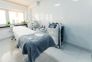 Comfortable SPA bed placed in a bright treatment room waiting for various clients. Professional equipment and gear used in thermolifting, facials, fractional lasers and more. Healthcare and medicine