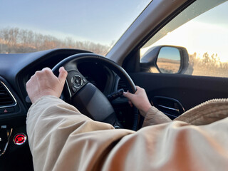Side view of woman's hands holding steering wheel when driving 