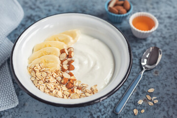 Domowe, zdrowe śniadanie. Jogurt naturalny z płatkami owsianymi, bananem i migdałami. - obrazy, fototapety, plakaty