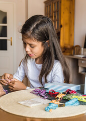 Little girl making hand made thread bracelets at home