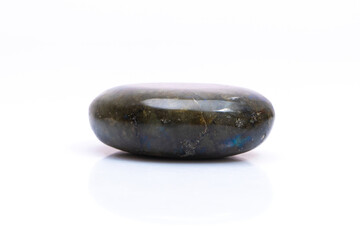 Natural gemstone labradorite isolated on white background. Dark gray labradorite with an inner iridescent glow on a white background