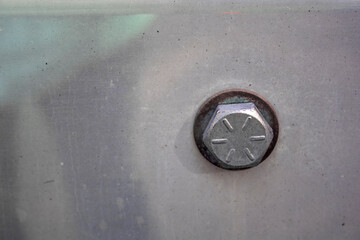 close up of an industrial bolt head fasten to a metal plate with a washer