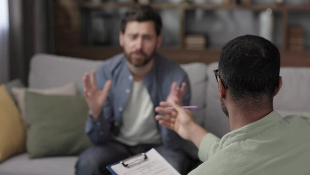 Visit to a psychologist. A man sits on a couch and talks to a psychotherapist. The patient is depressed, apathetic and stressed from problems in his personal life. Help of a psychologist.