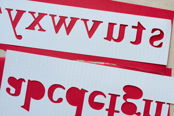 stencil with letters cutout (verso) on red and beige paper