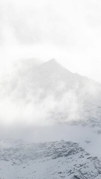 Vertical shot of foggy snow-covered mountains in Bormio, Italy