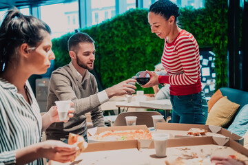 Eating pizza with diverse colleagues in the office, happy multi-ethnic employees having fun together during lunch, enjoying good conversation, and emotions