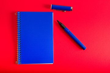 Blue spiral bound notepad pen  on red background
