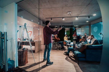 A bearded man in a modern office explaining to his young diverse team how a drone working 