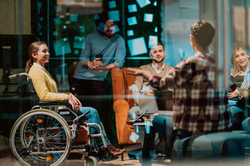 Businesswoman in wheelchair having business meeting with team at modern office. A group of young freelancers agree on new online business projects