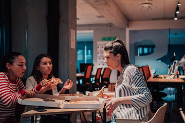 Eating pizza with diverse colleagues in the office, happy multi-ethnic employees having fun together during lunch, enjoying good conversation, and emotions