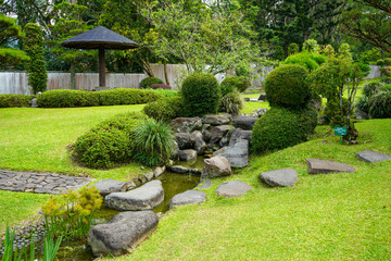 Traditional oriental park or garden from Japan or China with fish pond, lake or river, wooden bridge, meadow, and trees. Japanese garden design. Taman Bunga Nusantara, Cianjur, West Java, Indonesia.